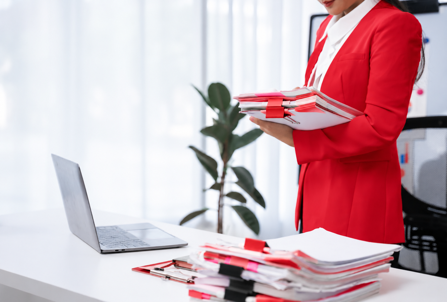 Office worker organizing documents beside a laptop